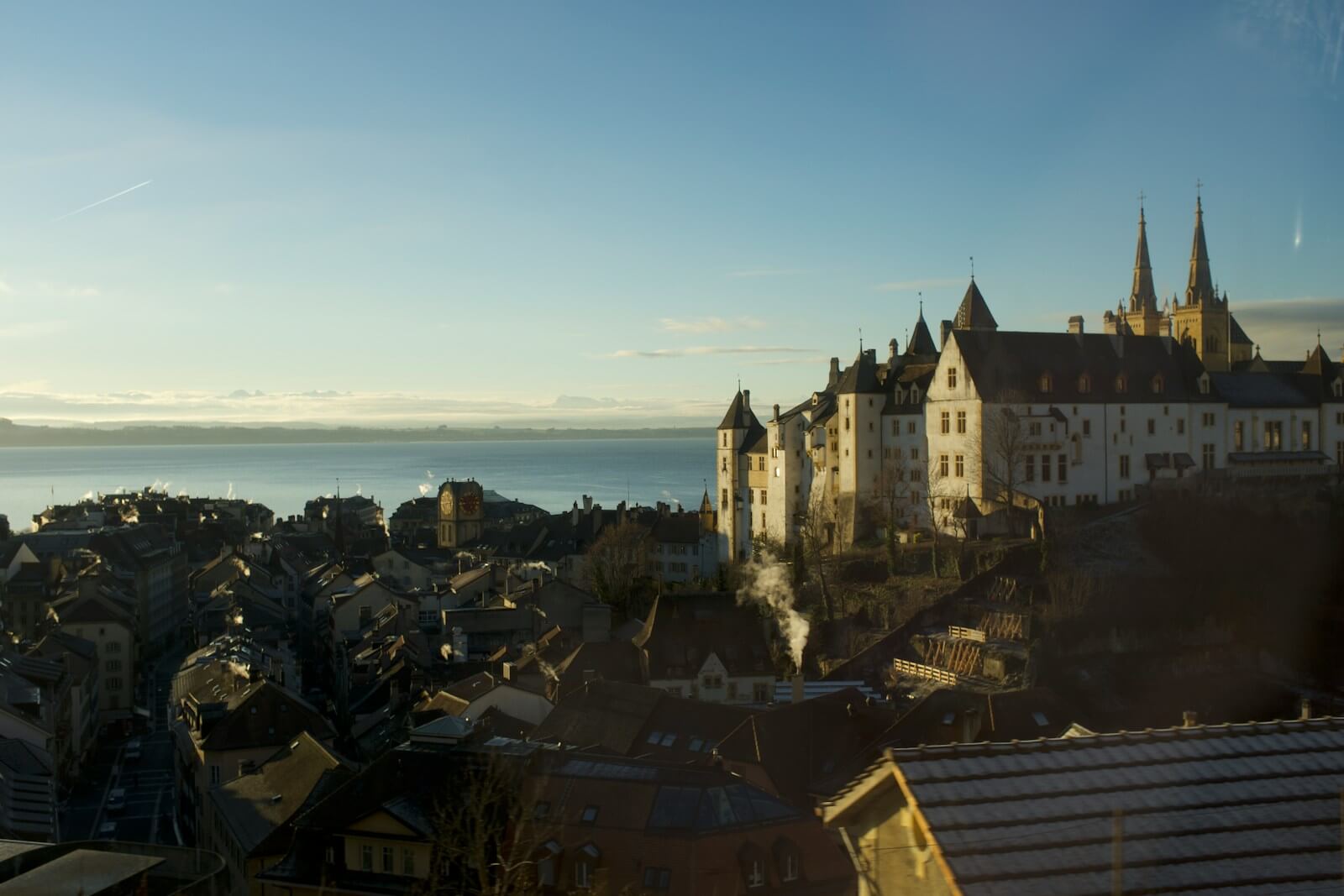A castle overlooks a town by the water.